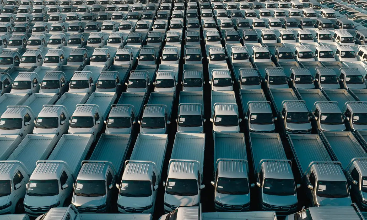 Overhead view of a corporate fleet of white pickup trucks parked in neat rows